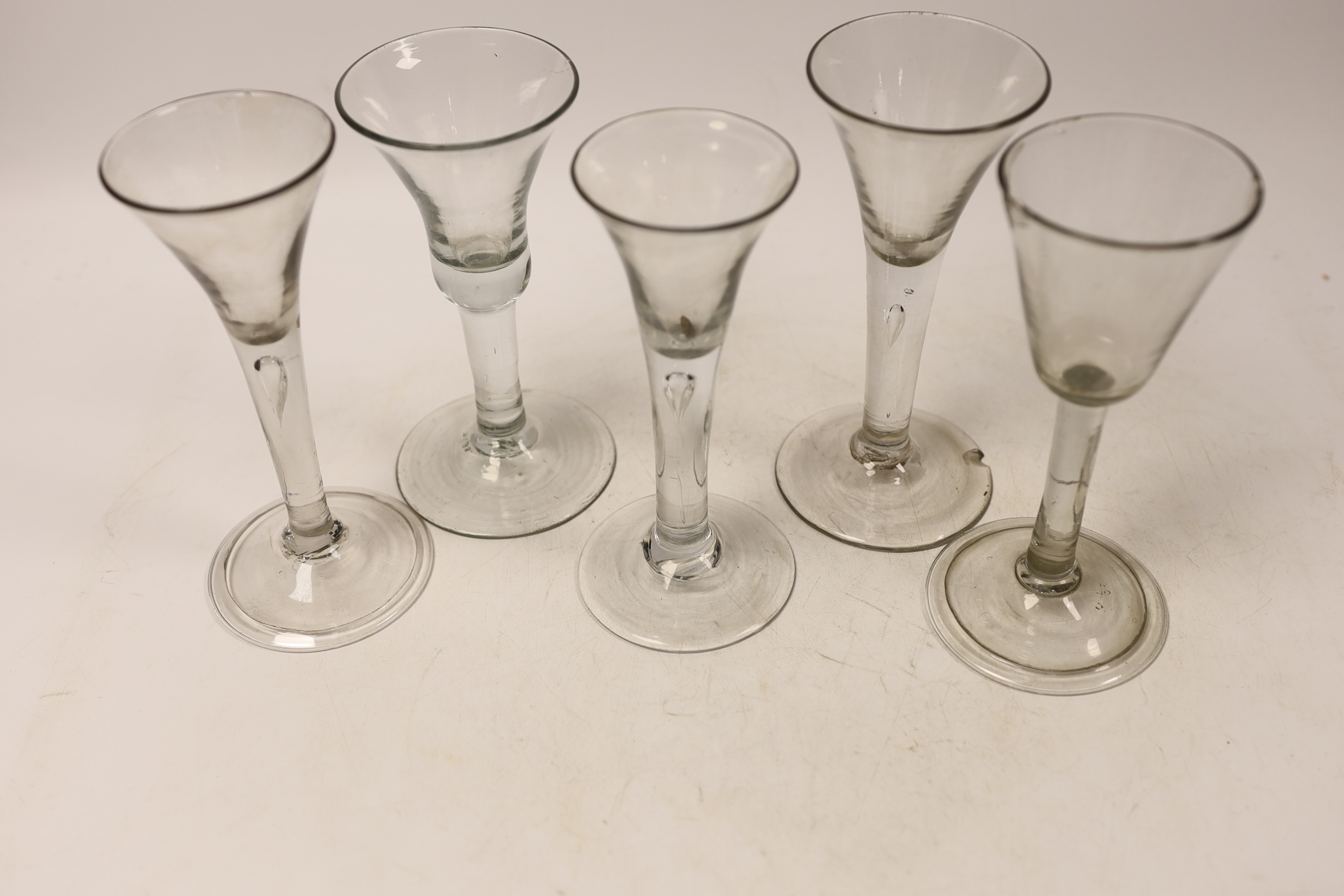 Five mid-18th century plain stem wine glasses, including three with drawn trumpet shaped bowls, two examples with folded feet, tallest 16cm